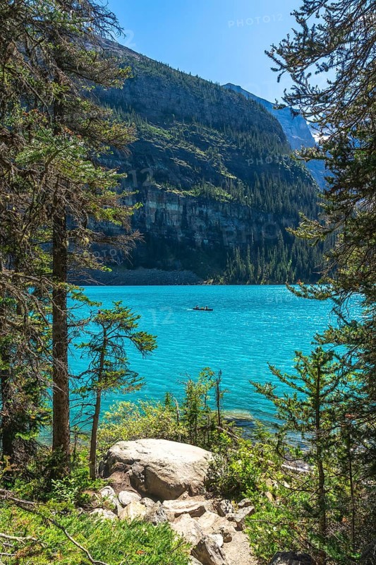 Tourists are canoeing on the turquoise, glacier fed moraine lake with the scenic valley of the ten peaks in the background in banff national park, canadian rockies, alberta, canada