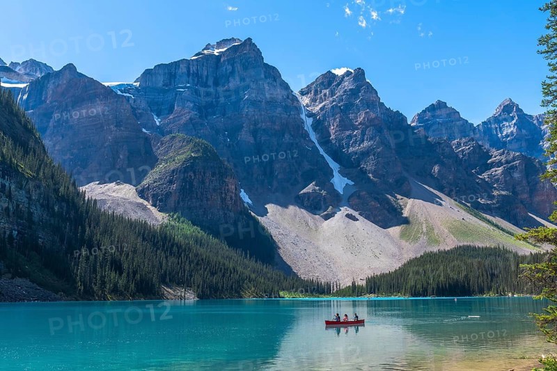 Breathtaking turquoise waters of moraine lake reflecting majestic mountains and glaciers in banff national park, with tourists enjoying canoe rides on a sunny day