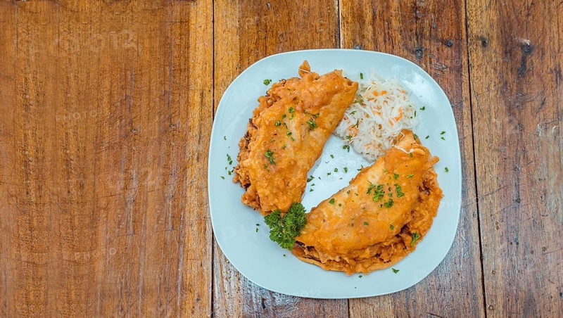 Enchilada with salad served in a plate on a wooden table, View of two enchiladas with salad served in a plate on a wooden table, Concept of traditional enchilada food