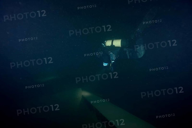 Diver examines a lediwreck, wreck of a lediship, ledi ship, cargo ship for mass freight, bulk cargo, at night in Lake Walen. Tauchplatz Känzeli, Mols, Canton of St. Gallen, Switzerland