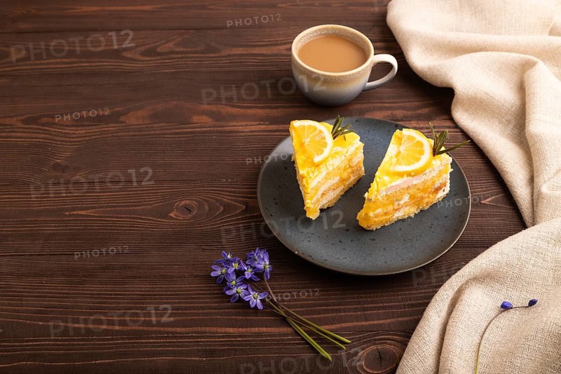 Lemon cake on brown wooden background and linen textile, cup of coffee, side view, copy space