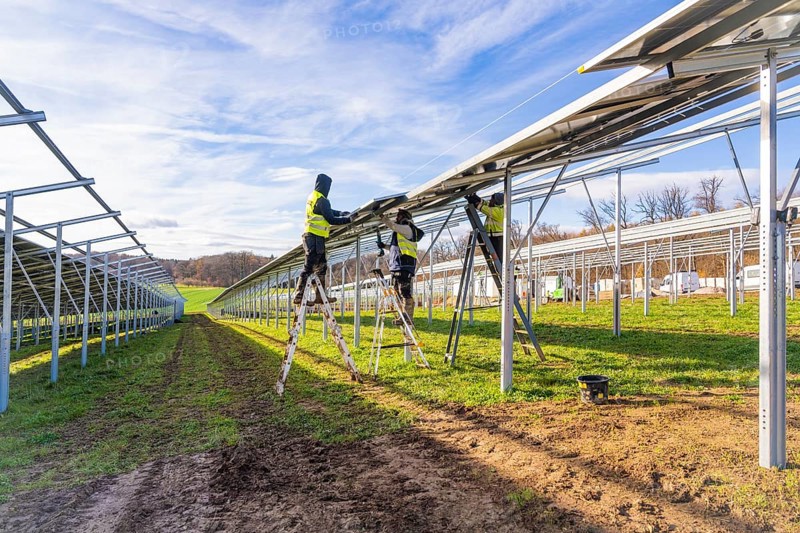 Workers install solar panels on a sunny day, Energiewende, construction of PV open space, Baden-Württemberg, Germany