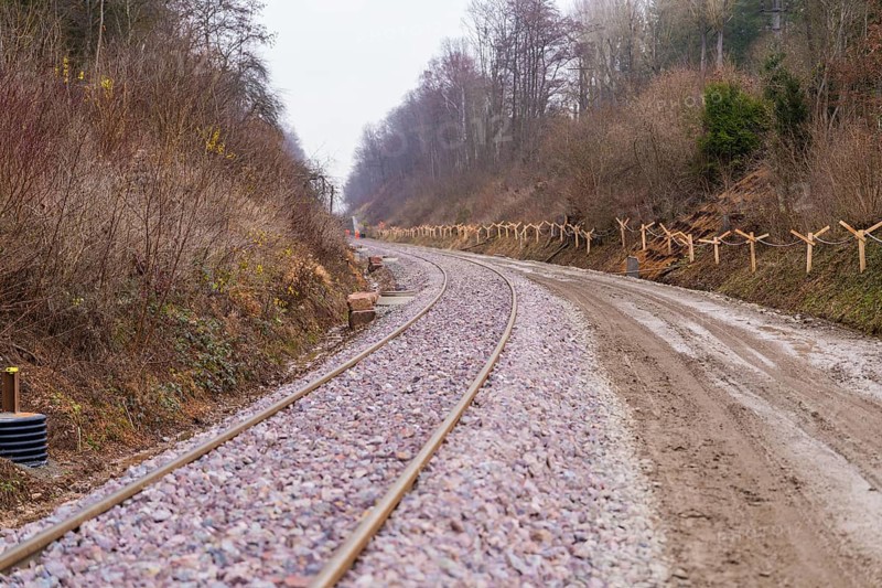 Curvy train tracks run through a quiet, wooded landscape with gravel, built by the Hermann Hesse Railway, Calw, Germany