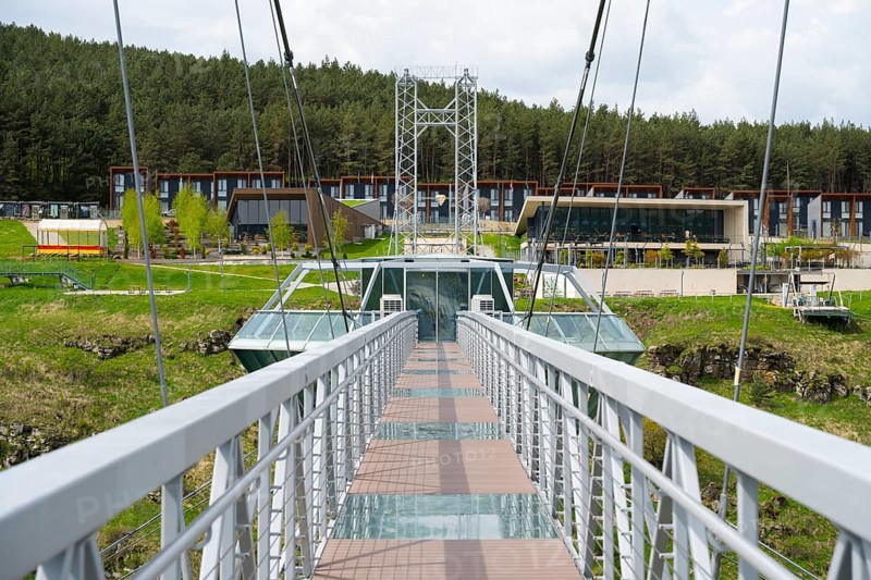 View of a modern suspension bridge with buildings in the background and surrounded by forest, Diamond Bridge, Diamond Glass Bridge, world's longest free-hanging structure, Dashbashi Gorge, Khrami River, Chrami, Tsalka Nature Reserve, Kartli, Georgia