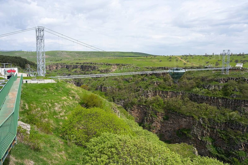 Wide landscape with modern bridge over green, rocky gorge under cloudy sky, Diamond Bridge, Diamond Glass Bridge, world's longest free-hanging structure, Dashbashi Gorge, Khrami River, Chrami, Tsalka Nature Reserve, Kartli, Georgia