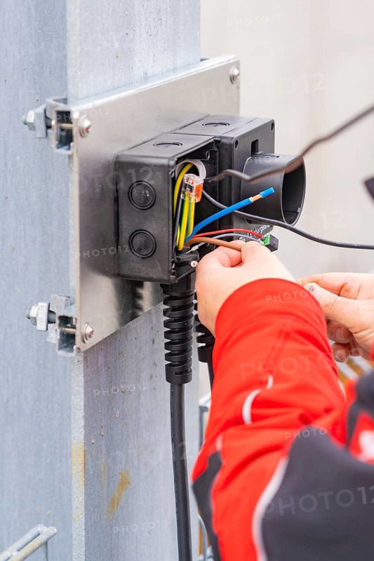 Detailed view of an electrician working on cables and connections, car park construction with charging infrastructure, Calw, Germany
