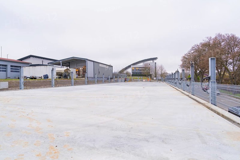 Industrial building in cloudy weather with an empty parking lot in the foreground, parking garage construction with charging infrastructure, Calw, Germany