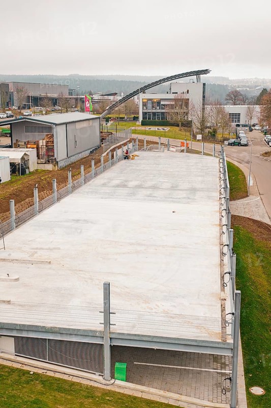 Aerial view of an empty parking lot with surrounding buildings and fences, parking garage construction with charging infrastructure, Calw, Germany