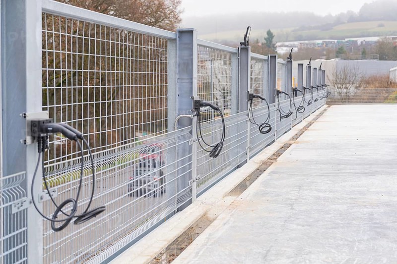 Cables run over a long fence on a concrete surface, with landscape in the background, parking garage construction with charging infrastructure, Calw, Germany