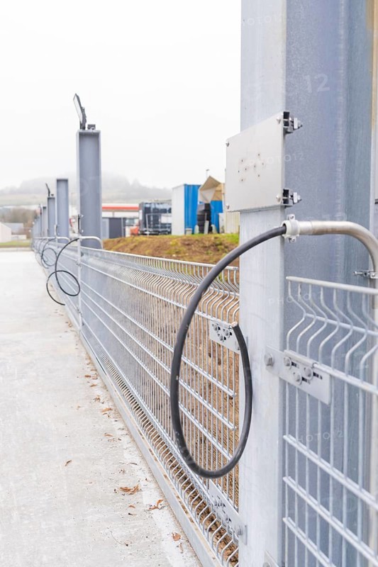 Electrical cable in front of a grey fence in an industrial area, parking garage construction with charging infrastructure, Calw, Germany