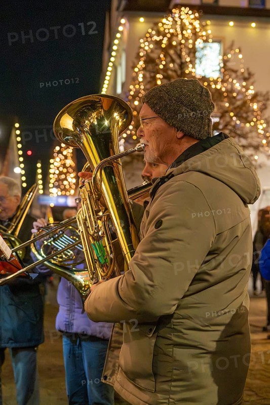 Tuba player in winter clothes on a street decorated with lights, Weihnachtsmark Nagold, LandkreiScalw, Germany