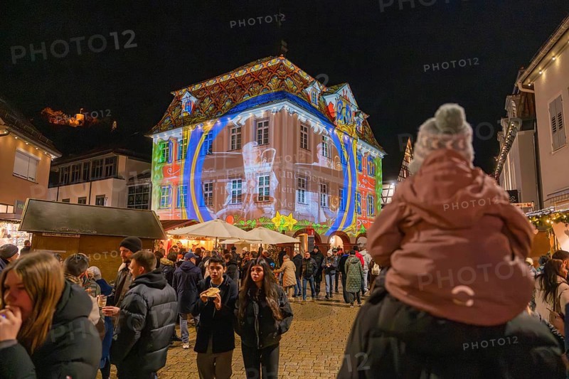 Families enjoy a night light projection onto a large building in a festive setting, Weihnachtsmark Nagold, LandkreiScalw, Germany