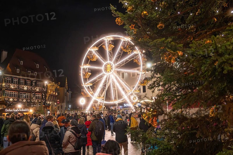 Illuminated Ferris wheel and half-timbered houses at night on a busy Christmas market, Weihnachtsmark Nagold, LandkreisCalw, Germany