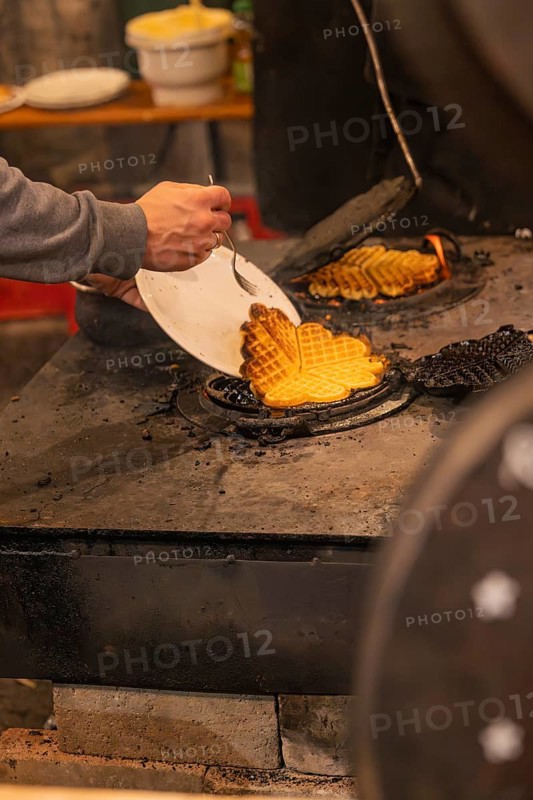 A person picks waffles baked fresh at a market from an oven, Weihnachtsmark Nagold, LandkreiScalw, Germany