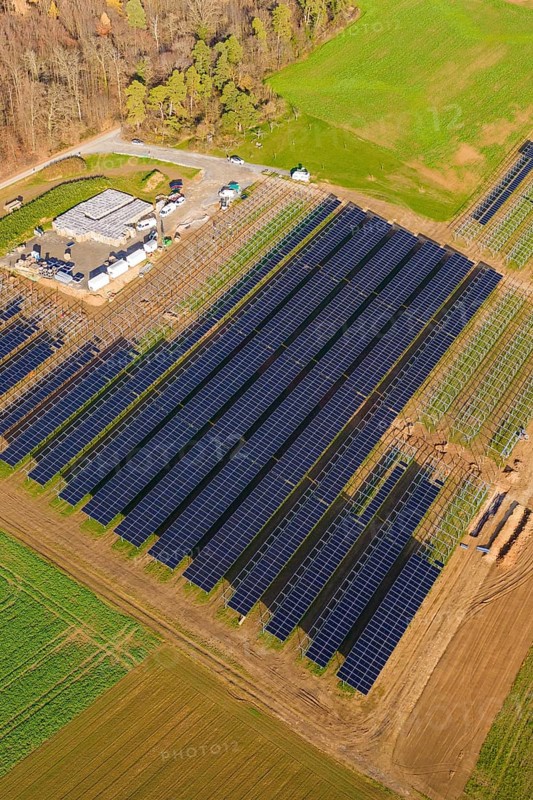 Aerial view of a large solar plant surrounded by autumn trees and fields, energy revolution, construction of PV open space, Baden-Württemberg, Germany