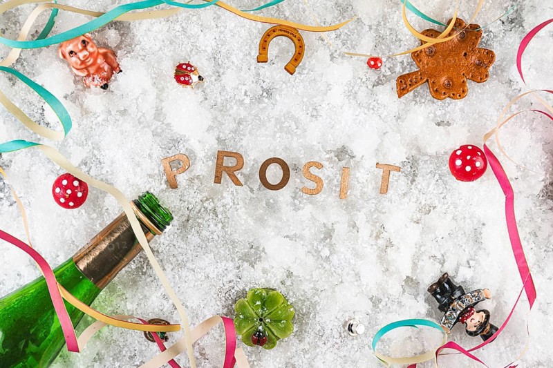 Cheers in the snow surrounded by lucky charms and champagne bottle, New Year's Eve
