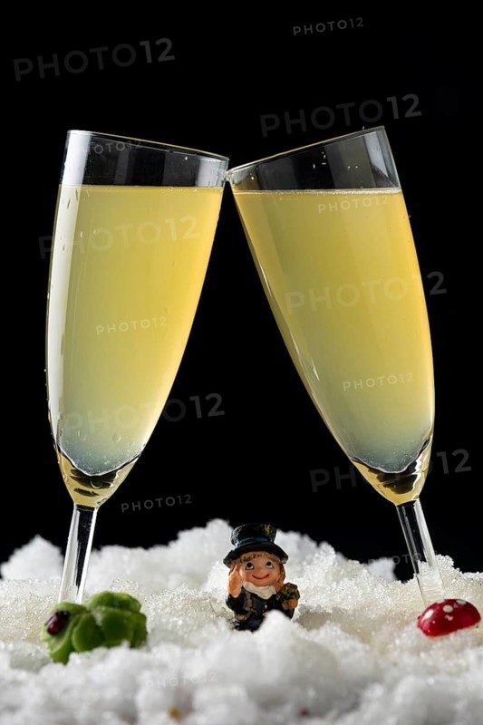 Two champagne glasses in the snow surrounded by lucky New Year's Day charms
