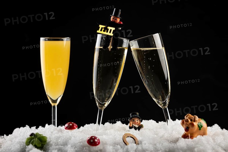 Three champagne glasses with lucky charms for New Year in the snow