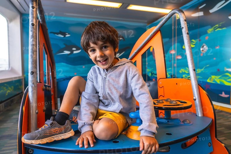 Happy child smiling and playing on a colorful play structure aboard a ferry traveling from victoria to vancouver, enjoying onboard entertainment during a scenic journey