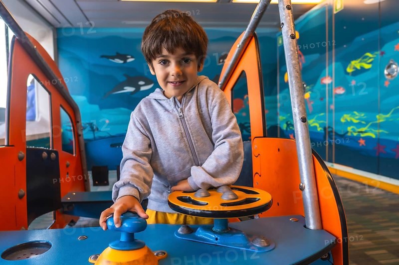 Young boy enjoying playing captain on a ferry boat traveling from victoria, vancouver island, to vancouver, british columbia, navigating imaginary waters with a playful smile