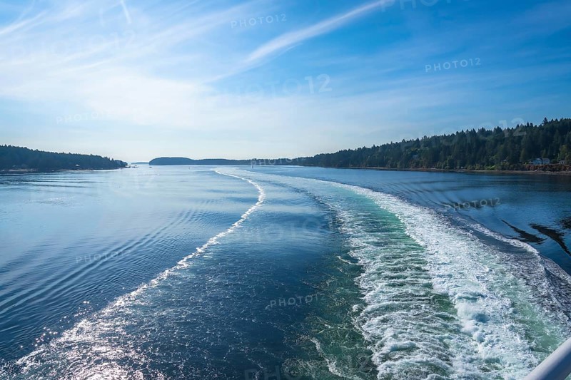 Churning white foam and turquoise water create a scenic wake as a ferry crosses the strait of georgia on a sunny day near vancouver island and vancouver