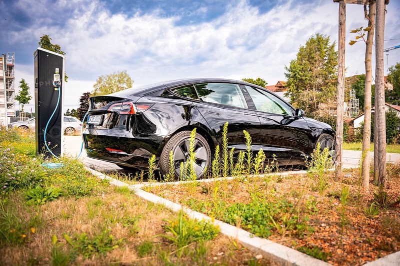 Black car at a charging station in a sunny, urban area, Deer e-Carsharing, Tesla Model 3, Calw, Germany