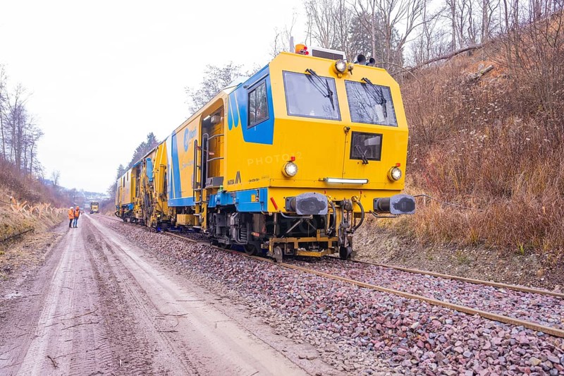 Yellow working trains on railroad tracks in a wintry landscape with gravel, stuffing machine on Hermann, Hesse, railway, Althengstett, Calw district, Germany