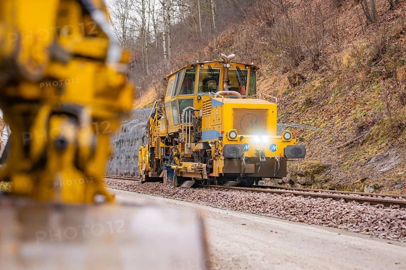Rail construction machine in use on railroad tracks, indicated blur in the foreground, stuffing machine on Hermann, Hesse, Bahn, Althengstett, Calw district, Germany