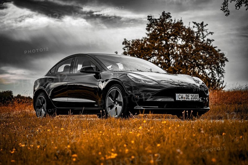 Black car parked on country road, dramatic clouds in the sky surrounded by meadows, Deer E-Carsharing, Tesla Model 3, Calw, Germany