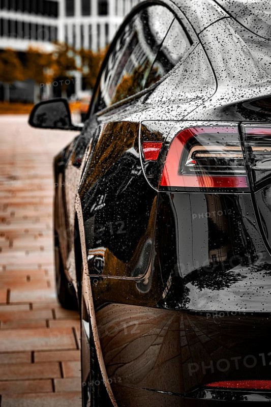 Close-up of a black vehicle with a rain-wet surface in an urban environment, Deer E-Carsharing, Tesla Model 3, Calw, Germany