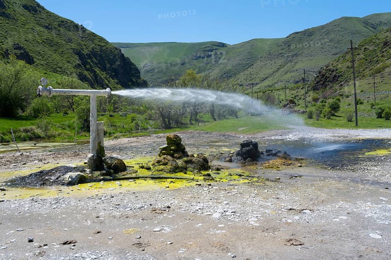 Natural spring with sparkling water jet against green mountain landscape under blue sky, Vardzia, Vardzia, Samtskhe—Javakheti region, Samtske Javacheti, Lesser Caucasus, Georgia