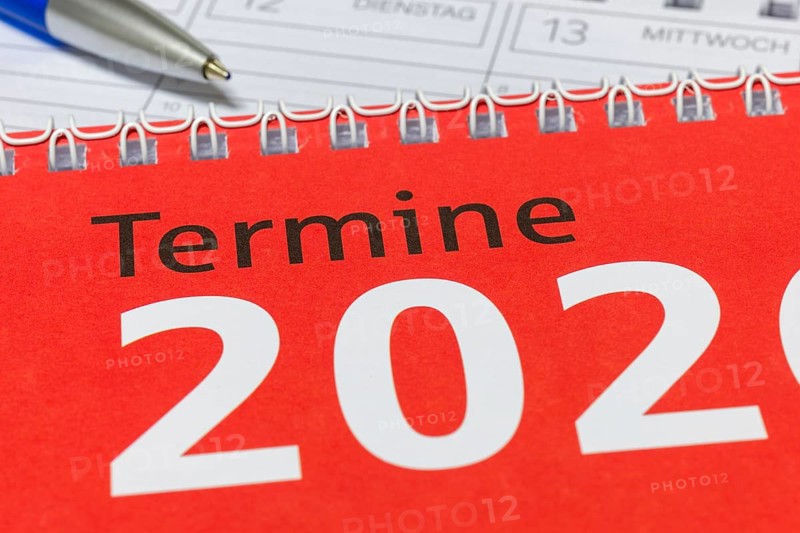 Close-up of a red calendar for 2026 with spiral binding and blue pen, diary