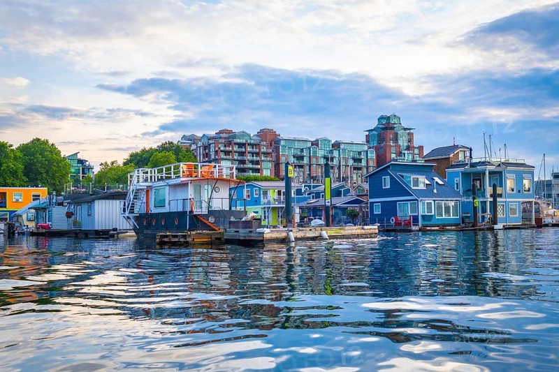 Colorful floating homes reflecting in the calm waters of fisherman's wharf park in victoria, british columbia, create a charming and picturesque scene on a sunny summer day