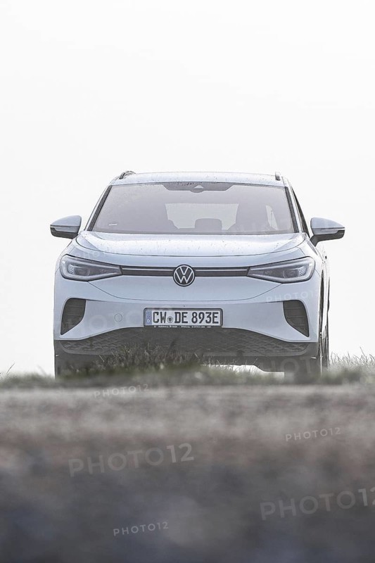 A white car seen from the front in a morning haze in an open landscape, VW ID4 electric car, Deer Carsharing, Calw, Germany