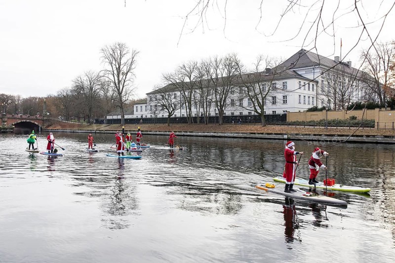 Water sports enthusiasts dressed up as Santa Claus ride SUPs on the Spree in front of Bellevue Palace in Berlin on 30.11.2025