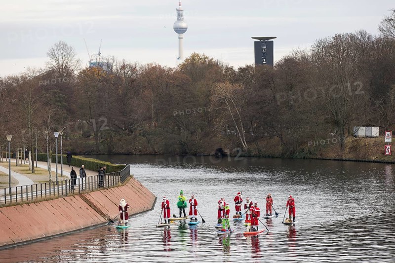 Water sports enthusiasts dressed up as Santa Claus ride SUPs on the Spree am Park at the presidential triangle in Berlin on 30.11.2025