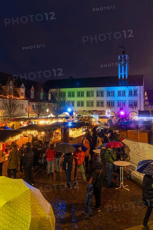 Colourfully lit Christmas market with people and umbrellas in a nighttime urban landscape, Böblingen Christmas market, Germany