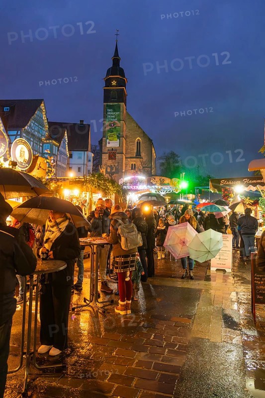 Lively Christmas market in rain with people and illuminated church in the background, Böblingen Christmas market, Germany