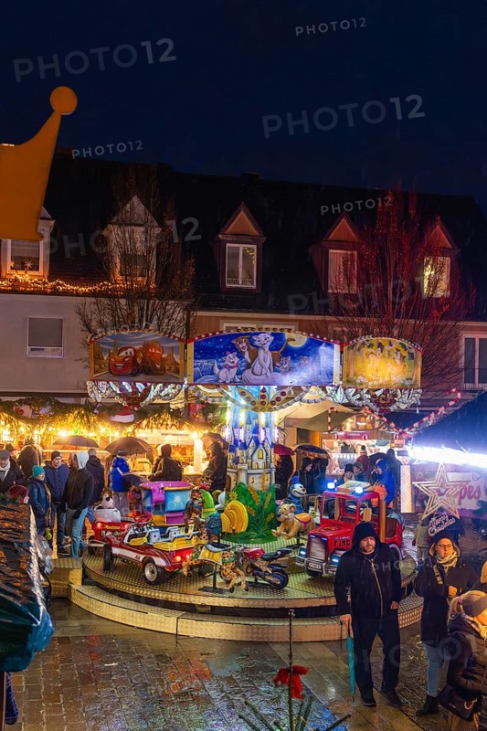 Families in front of an illuminated carousel with toys at a night-time Christmas market, Böblingen Christmas market, Germany