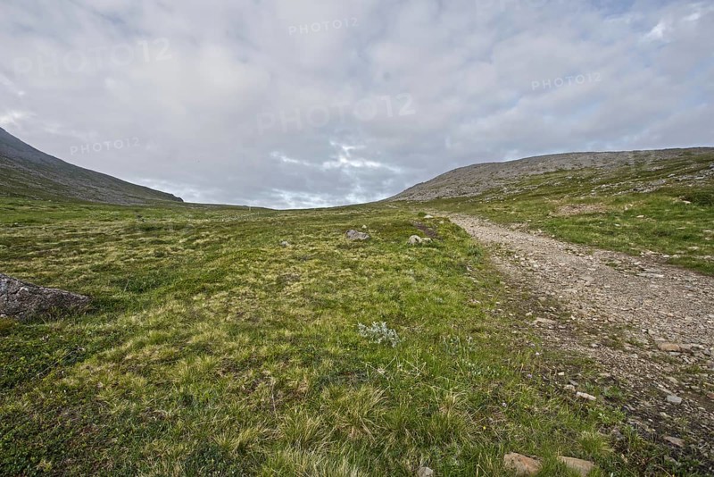 Rocky path through green hills under overcast sky, Nordkapp
