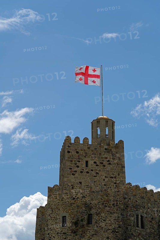 A stone castle with a Georgian flag flies on the tower against a clear blue sky, Rabati Fortress, Akhaltsikhe, Samtskhe-Javakheti region, Samtskhe-Javakheti, Georgia