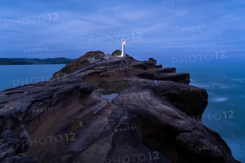 Castlepoint lighthouse on a rock, ocean, evening, blue hour, illuminated, long exposure. Castlepoint, Wairarapa Coast, Wellington Region, North Island, New Zealand