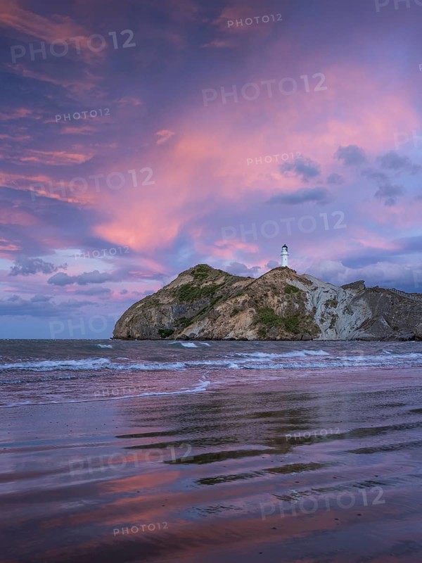 Castlepoint Beach, ocean and lighthouse on a rock, evening, sunset, dramatic sky. Castlepoint, Wairarapa Coast, Wellington Region, North Island, New Zealand