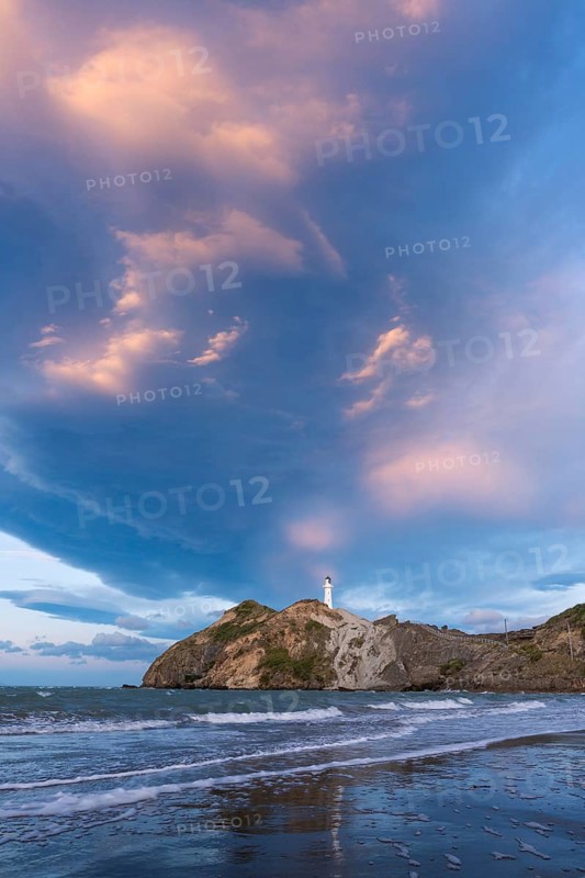 Castlepoint Beach, ocean and lighthouse on a rock, in the evening, dramatic sky. Castlepoint, Wairarapa Coast, Wellington Region, North Island, New Zealand