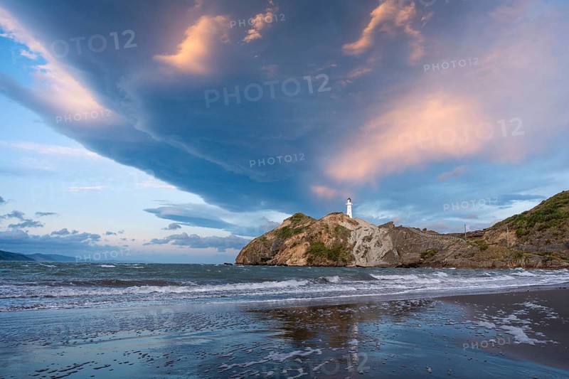 Castlepoint Beach, ocean and lighthouse on a rock, in the evening, dramatic sky. Castlepoint, Wairarapa Coast, Wellington Region, North Island, New Zealand