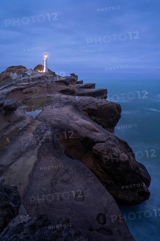 Castlepoint lighthouse on a rock, ocean, evening, blue hour, illuminated, long exposure. Castlepoint, Wairarapa Coast, Wellington Region, North Island, New Zealand