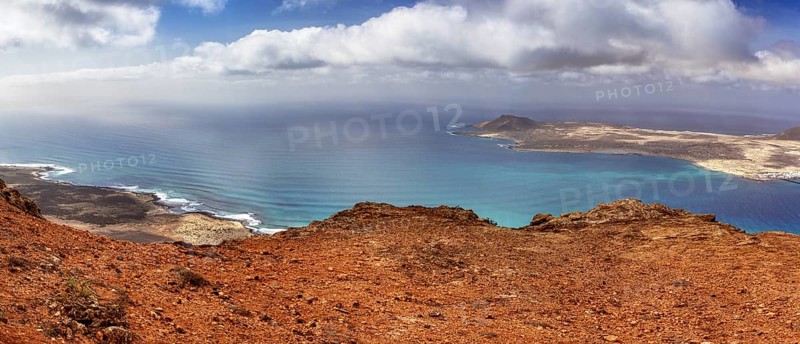 Wide coastline with blue ocean and sky, dotted with clouds overlooking La Graciosa, Haria Lanzarote, Canary Island