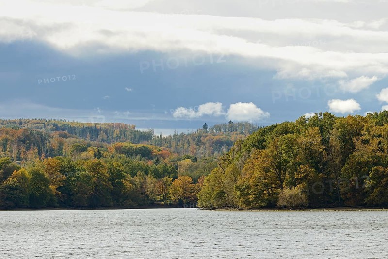View over Lake Möhnesee, mixed autumn forest on the shore, rising rain clouds, Möhnetalsperre, North Rhine-Westphalia, Germany