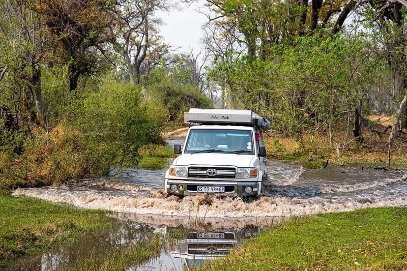 Safari car, off-road car driving through a river, Xakanaxa, Moremi Game Reserve, Botswana
