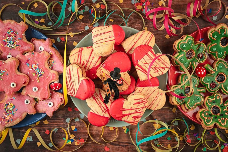 Various colorful cookies on wooden table with confetti, streamers and lucky charms